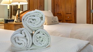 A neatly made bed with a folded towel stack, a bedside lamp, and a pillow with text. - Ski In and Out Condo in Lionshead Village w/ Pool, Hot Tubs, and Lovely Views (Vail)