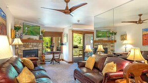 A spacious living room with leather sofas, a fireplace, and a television mounted on the wall. - Ski In and Out Condo in Lionshead Village w/ Pool, Hot Tubs, and Lovely Views (Vail)