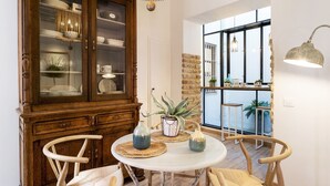 Un comedor con una mesa redonda, sillas de madera, un aparador con puertas de cristal y vistas a través de un ventanal.