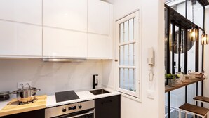 Una cocina moderna con armarios blancos, una estufa negra y un ventanal con vistas.