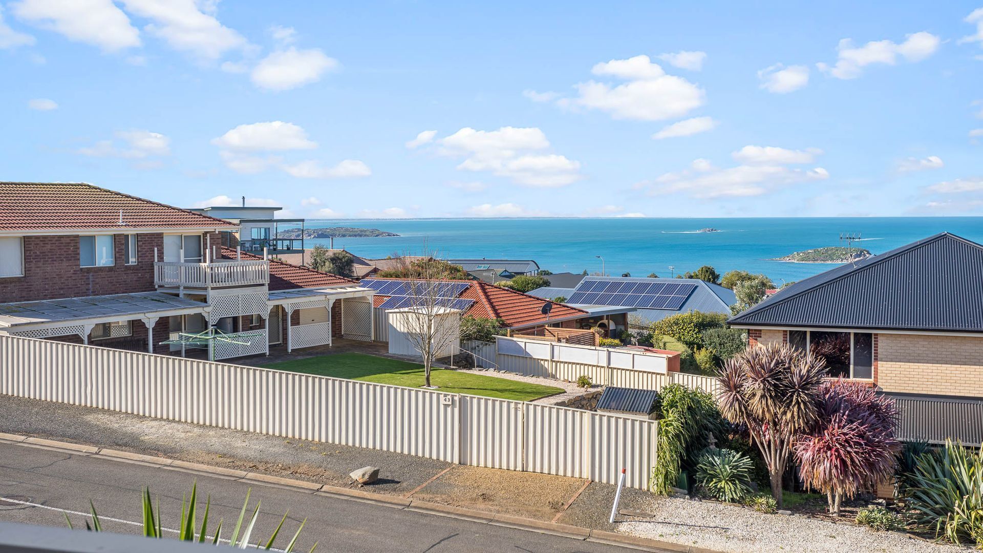 Un quartier résidentiel avec des maisons, des panneaux solaires et une vue sur la mer.