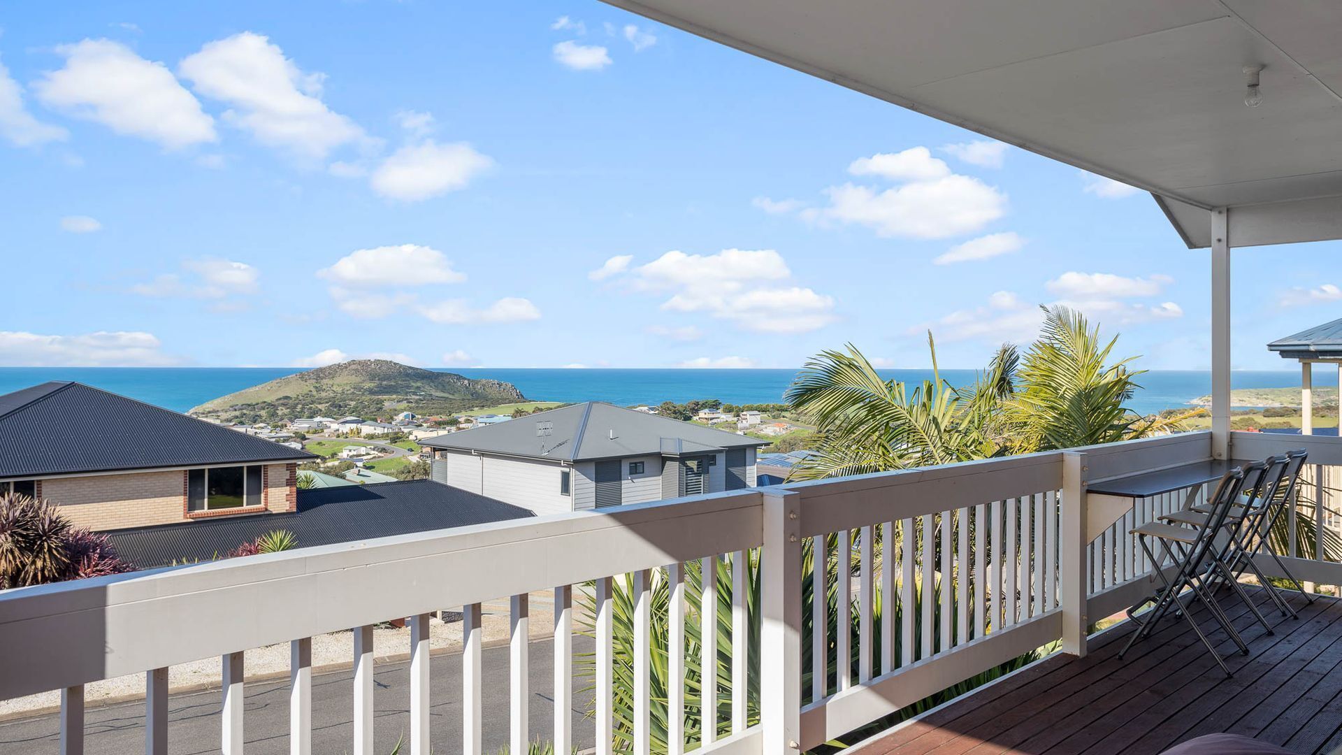 A balcony with a view of the ocean and a hill in the distance.