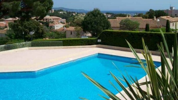 Una piscina con vistas despejadas a la zona residencial y al mar al fondo.