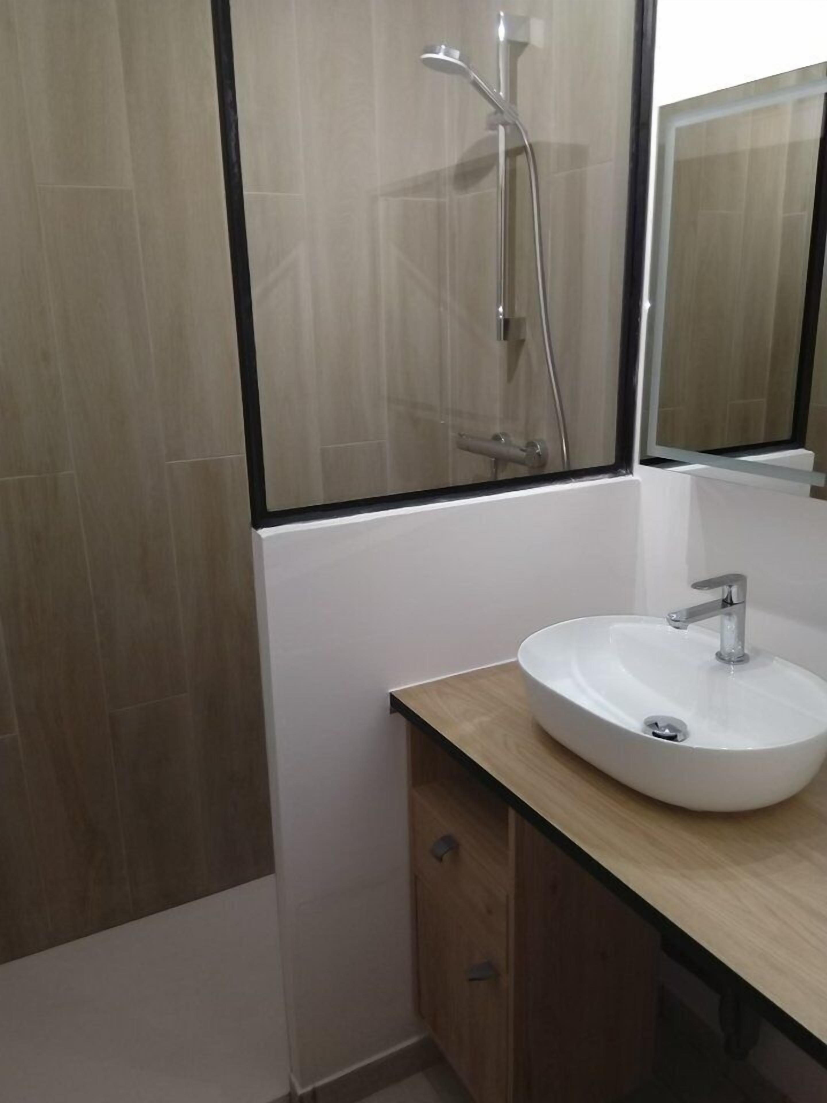 Une salle de bain avec un lavabo blanc, un miroir et une douche.