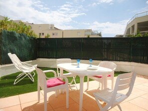 An outdoor patio with a round table and white chairs, a black fence, and a green hedge. - Nice flat 4 people near centre and beach (CAVALAIRE sur mer)