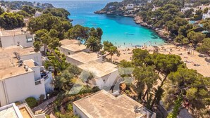 A coastal town with a beach, white buildings, and green trees. - B23. Beachfront apartment with pool, AC, wifi (Cala d'Or)
