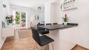 A modern kitchen with a black countertop, white cabinets, and a built-in shelf with colorful glassware. - B23. Beachfront apartment with pool, AC, wifi (Cala d'Or)