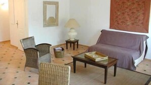 Un salon comprenant un canapé, deux fauteuils, une table basse, une lampe et un miroir.