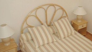 Un lit avec une couvre-lit à rayures et des oreillers, flanqué de deux tables de chevet sur lesquelles sont posées des lampes.