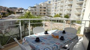 Een balkon met een tafel en stoelen, met uitzicht op een woongebied met appartementen.