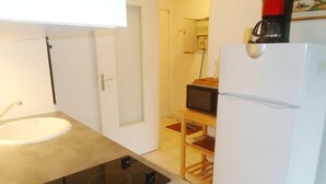 A compact kitchen with a white sink, a black stovetop, a microwave, and a white refrigerator. - 2-room air-conditioned apartment, swimming pool (CAVALAIRE sur mer)
