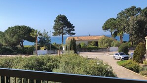 A coastal property with a paved driveway, parked cars, and a view of the sea. - Studio with separate bedroom. Terrace sea view. Bay of Sagone (Sagone)
