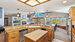 Una cocina amplia con una isla grande, armarios de madera y vistas al exterior.