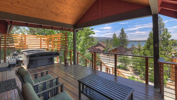 Terraza exterior cubierta con una parrilla, asientos y vistas a un lago y montañas.