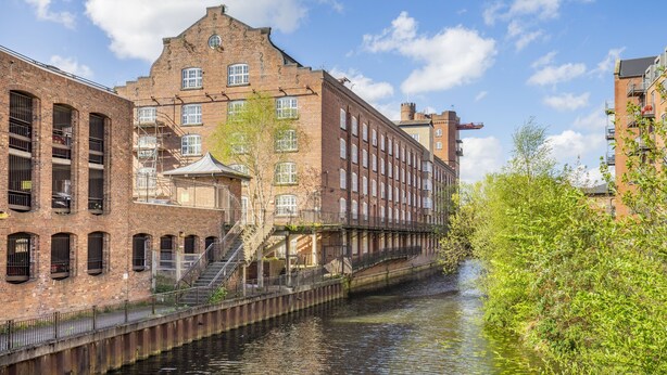 A canal-side building with multiple windows, a staircase, and a bridge over the water.