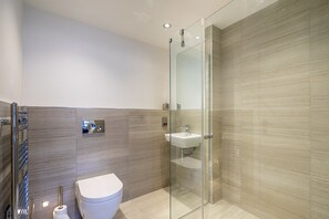 Ein modernes Badezimmer mit Duschkabine aus Glas, Toilette und Waschbecken.
