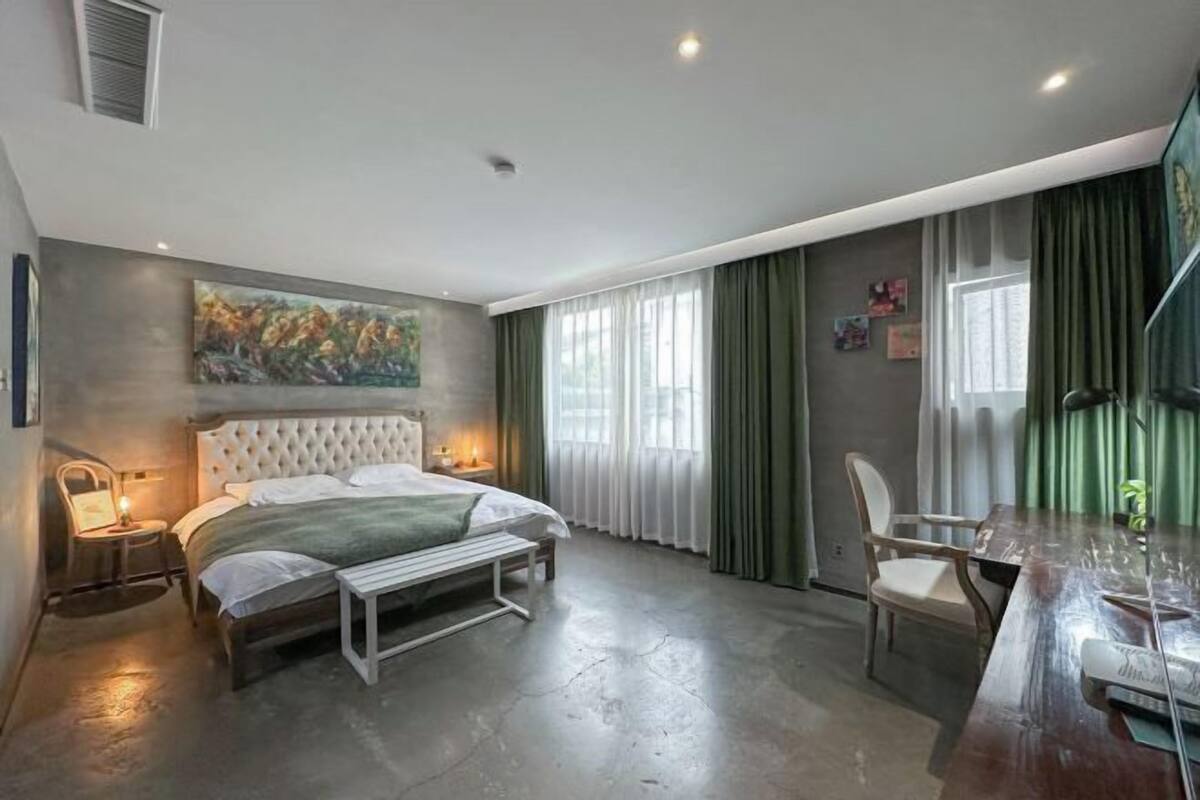 A bedroom with a large bed, a desk, and a chair.