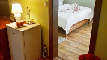 Un dormitorio con cama, mesita de noche, lámpara y un pequeño refrigerador.
