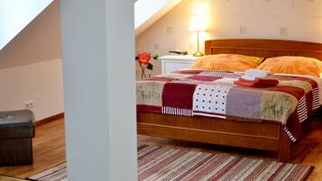 Une chambre à coucher avec un lit en bois, une table de chevet, une lampe et une fleur rouge posée sur la table de chevet.
