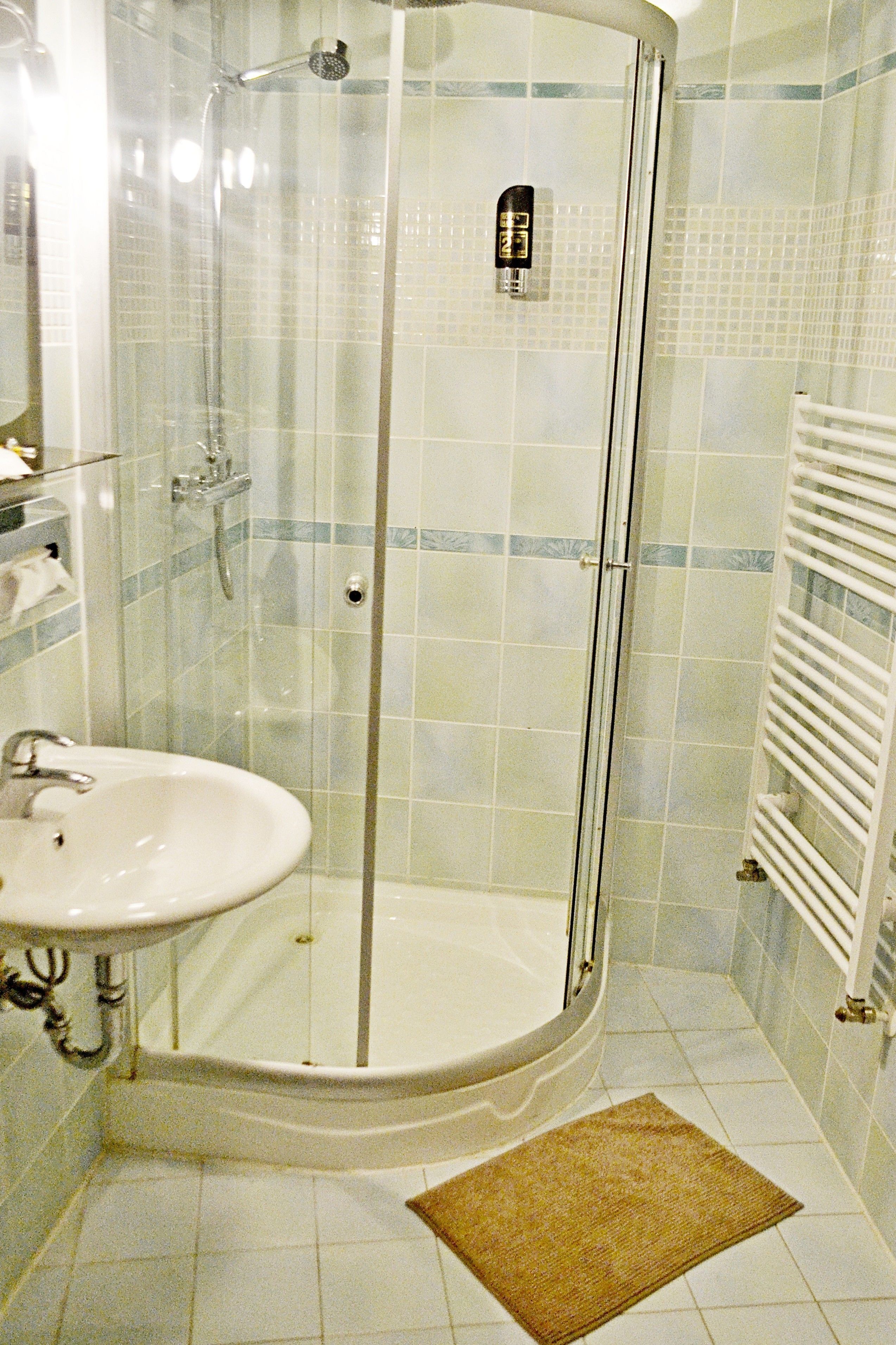 A bathroom with a glass-enclosed shower, a sink, and a towel rack.