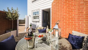 An outdoor patio with wicker furniture, a table set with drinks, and a bottle of champagne.
