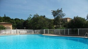 A clear blue swimming pool with a white fence and a small building in the background. - Contemporary apartment with air conditioning in a residence with swimming-pool (CAVALAIRE sur mer)
