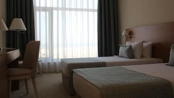 A hotel room with two beds, a desk, and a chair.