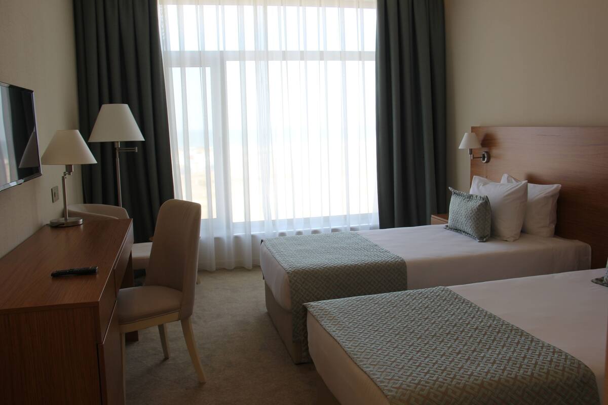 Une chambre d’hôtel avec deux lits, un bureau, une chaise et un téléviseur.