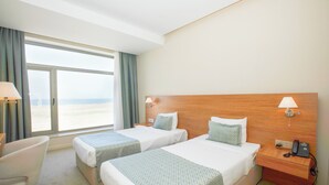 Une chambre d’hôtel avec deux lits, un bureau, une chaise et une grande fenêtre donnant sur un paysage agréable.