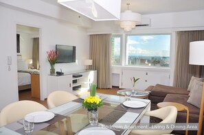 Relax in this stylish 1-bedroom apartment with a living and dining area, featuring a glass dining table and a comfortable sofa.