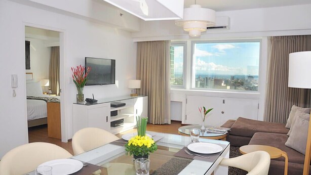 Un appartement d’une chambre comprenant un coin repas, un salon, une télévision et offrant une vue sur la ville.