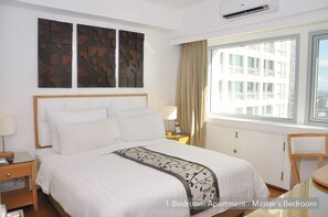 Enjoy a restful stay in this 1-bedroom apartment with a large bed, bedside table, and window with a view.