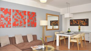 Un salon moderne avec un canapé, une table à manger et des chaises, ainsi que des œuvres d’art abstrait accrochées aux murs.