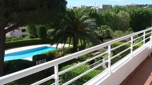 Ein Balkon mit Pool, umgeben von üppiger Vegetation und blauem Himmel.