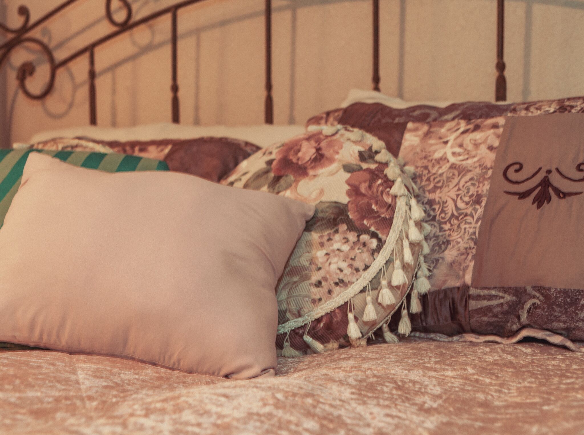A bed with a floral-patterned bedspread and decorative pillows.