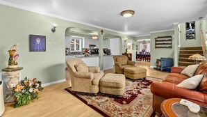 Una sala de estar con sofá, sillones, alfombra y un comedor con sillas y mesa.