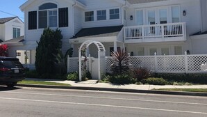 Uma casa de dois andares com fachada branca, uma varanda no segundo andar e um portão de entrada.
