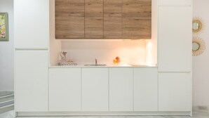 A modern kitchen with white cabinetry, a wooden upper shelf, and a marble countertop. - iloftmalaga Strachan-Larios (Málaga)