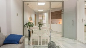 A modern living room with a sofa, a coffee table, and a glass partition leading to a kitchen area. - iloftmalaga Strachan-Larios (Málaga)