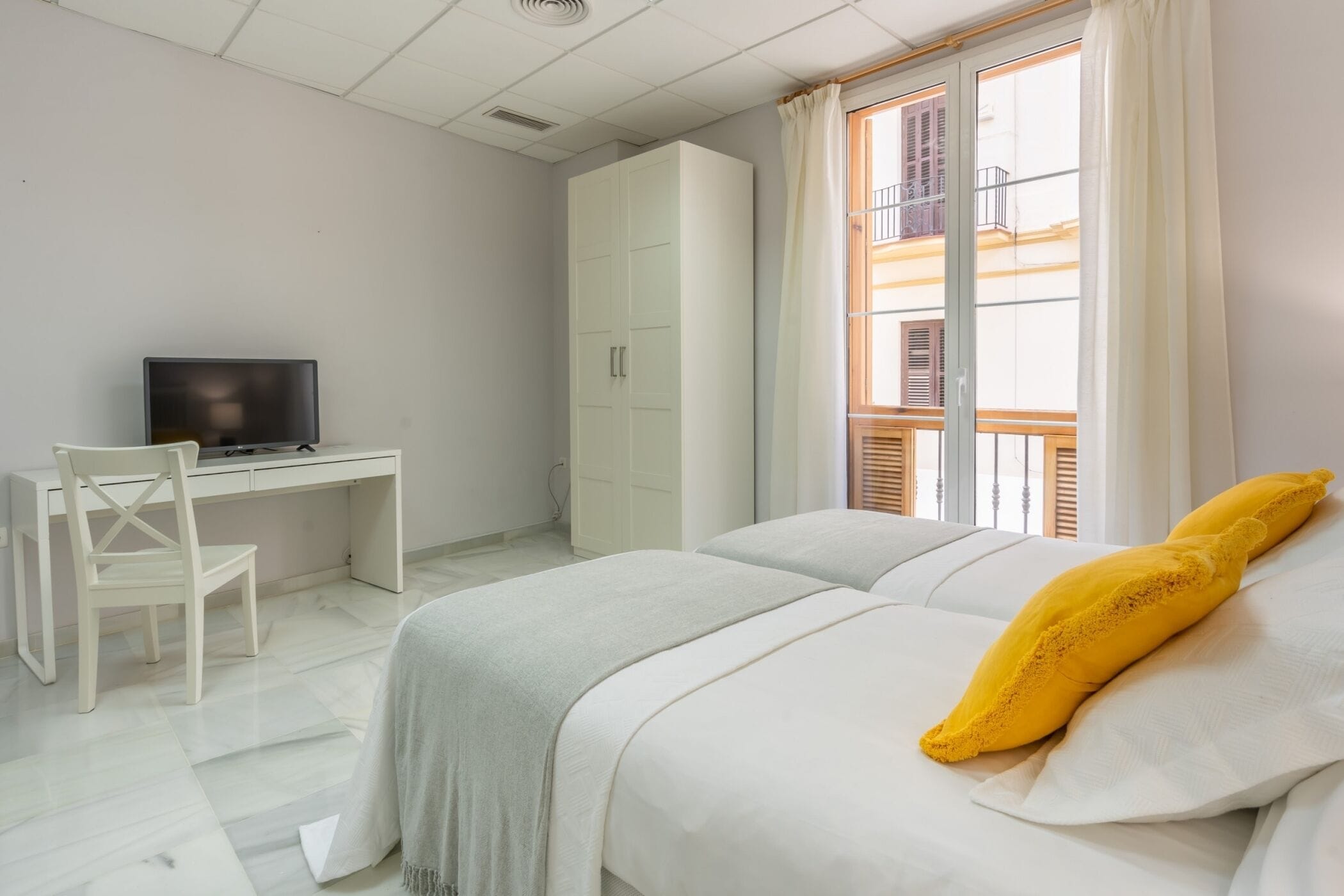 A bedroom with a bed, a desk, and a television.