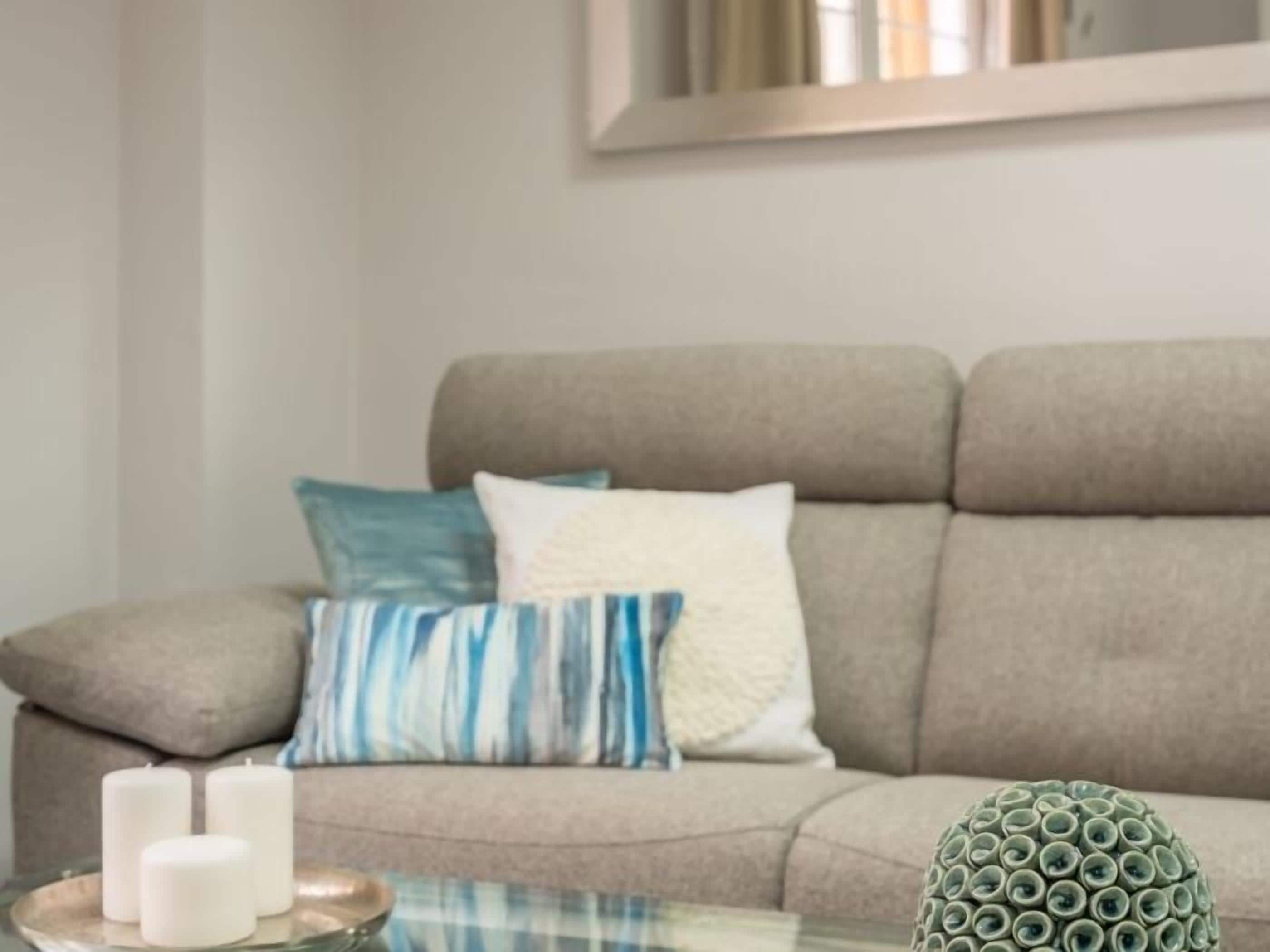 A living room with a beige sofa, a glass coffee table, and a decorative ceramic piece.
