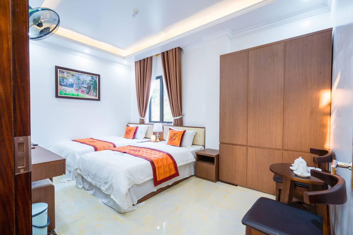 Quarto de hotel com uma cama grande, uma escrivaninha, uma cadeira e um guarda-roupa.