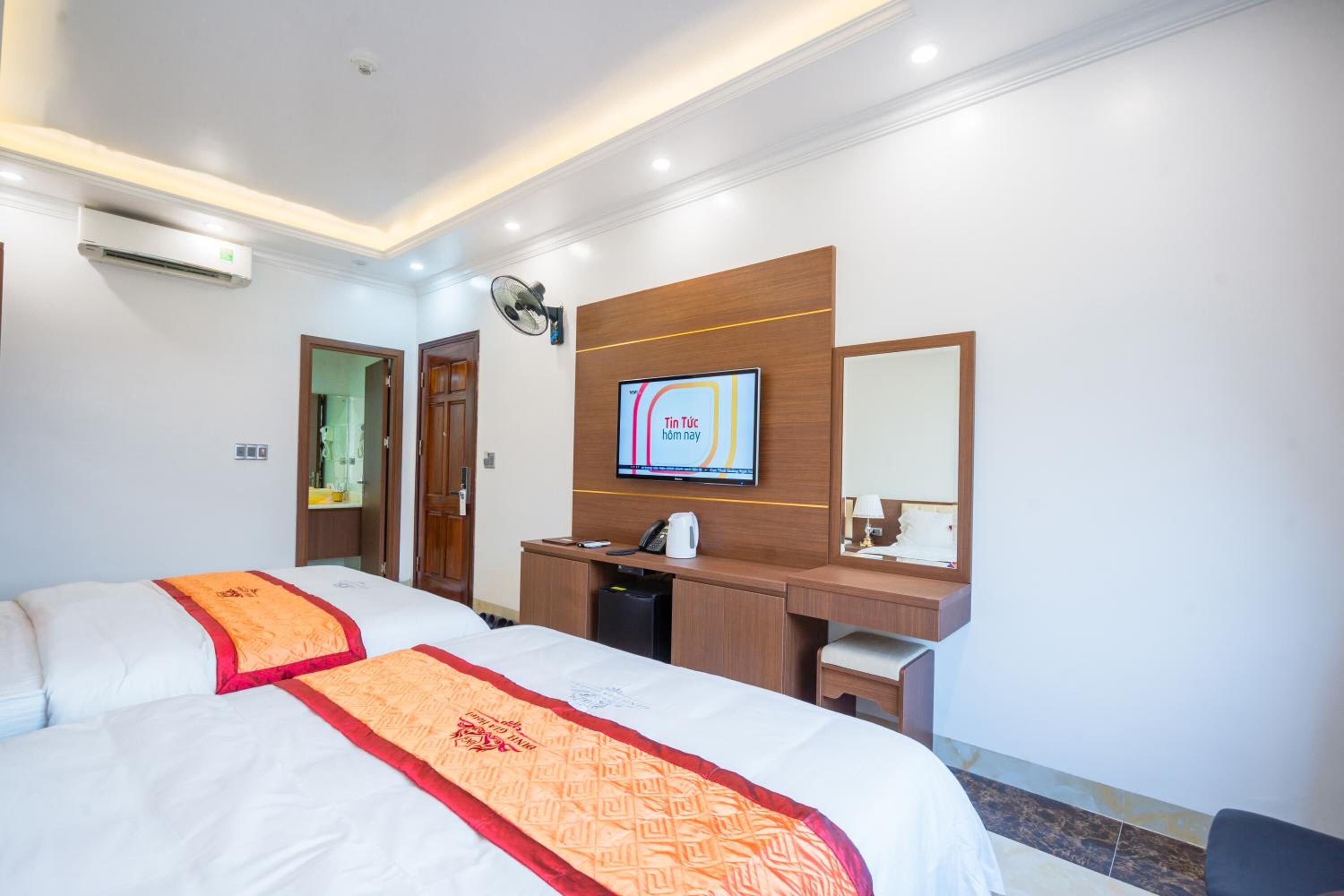 A hotel room with a large bed, a desk, a television, and a mirror.