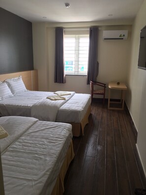 A hotel room with two beds, a small table, a chair, and a window with curtains. - Phuong Ly Ly Hotel (Ho Chi Minh City)