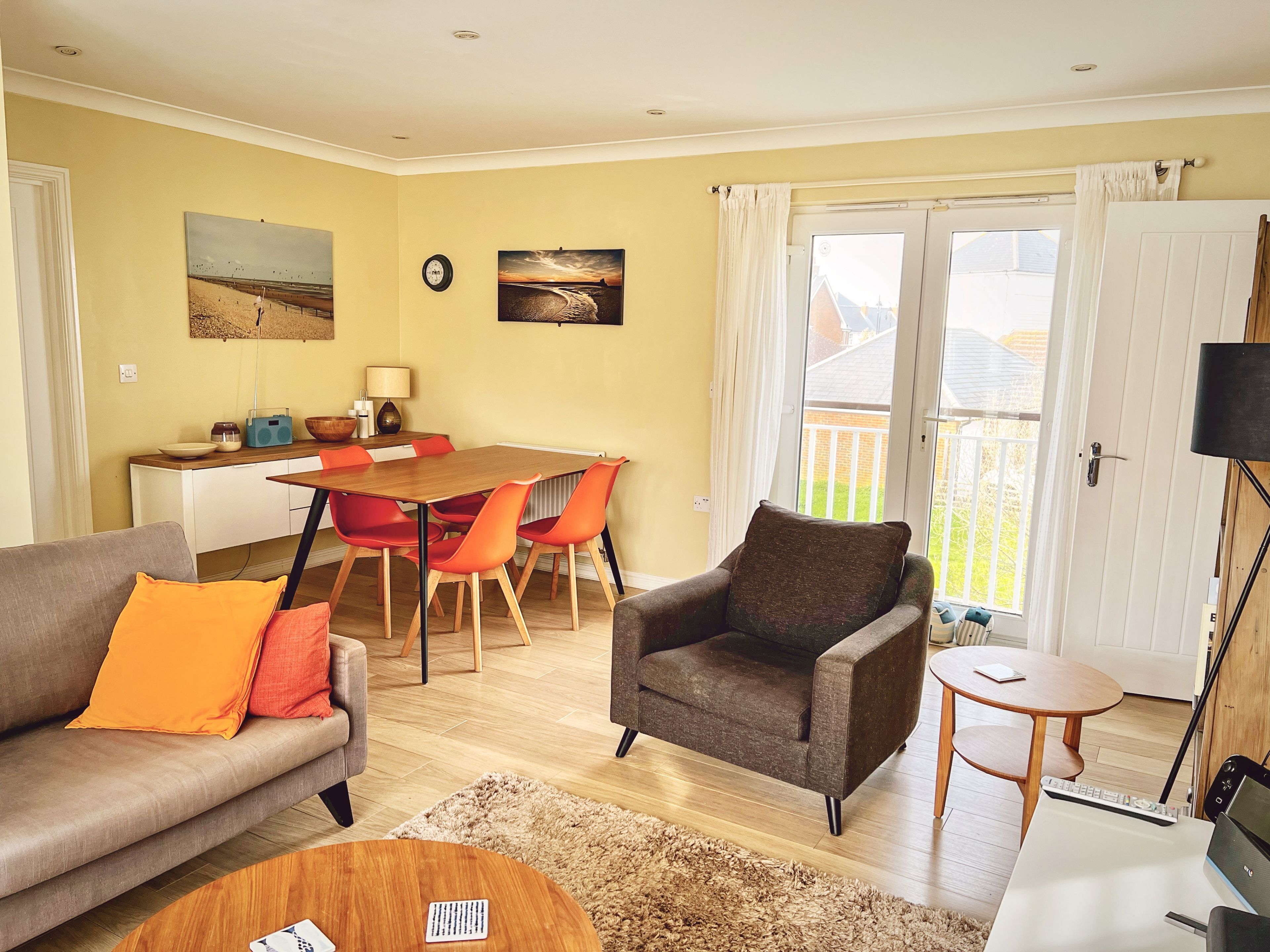 Un salon comprenant un canapé, un fauteuil, une table basse, une table à manger avec des chaises, et une vue sur l’extérieur grâce à une porte coulissante.