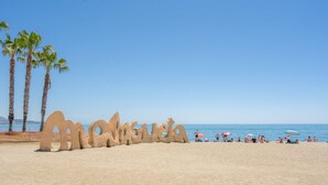 Una playa con una gran escultura de arena que dice 'Malagueta'.