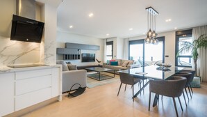 Una sala de estar moderna con televisor, sofá, mesa de comedor y sillas.