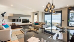Una sala de estar moderna con una mesa de comedor de vidrio, un sofá y un televisor montado en la pared.