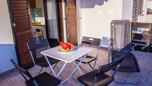 An outdoor patio with a table, chairs, and a glass partition. - DreamDay apartment (Vir)