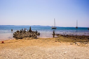 A rocky beach with boats in the water.